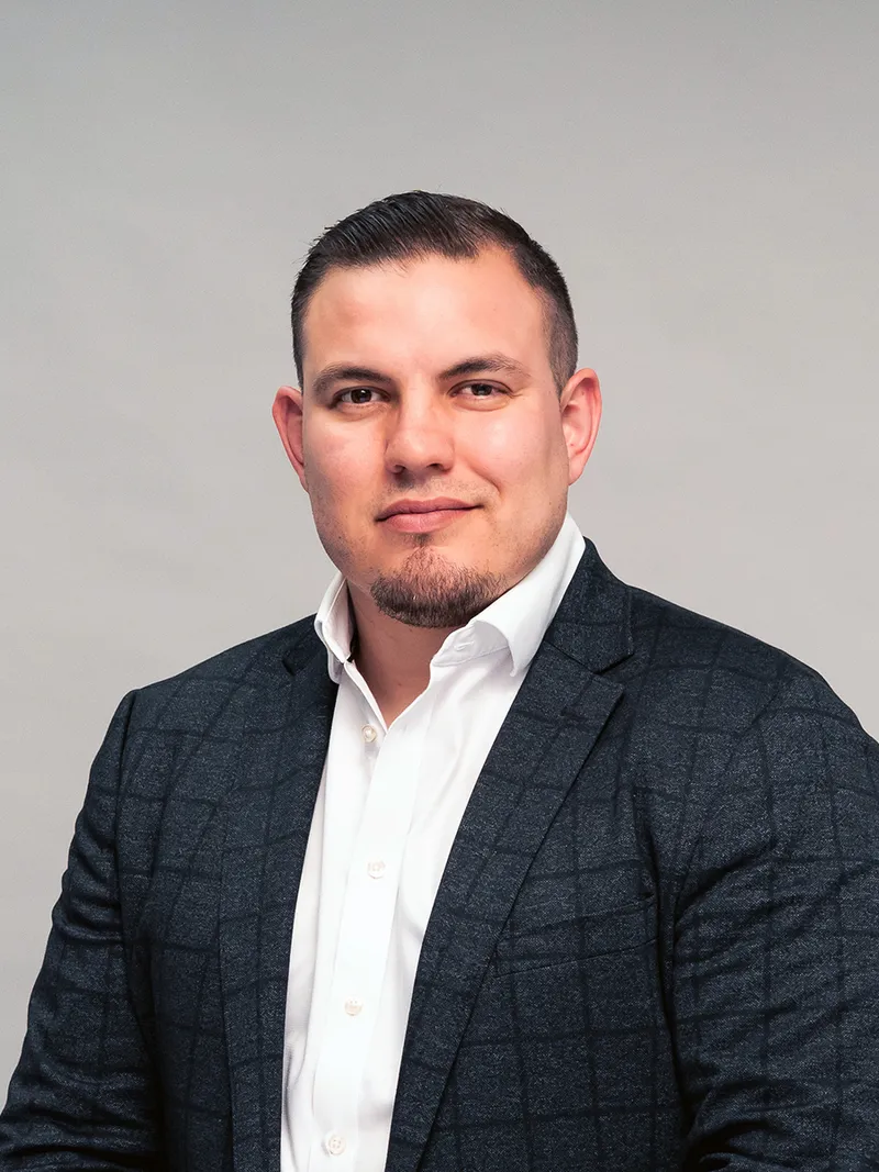 Corporate headshot of a man in a blazer against a gray studio backdrop