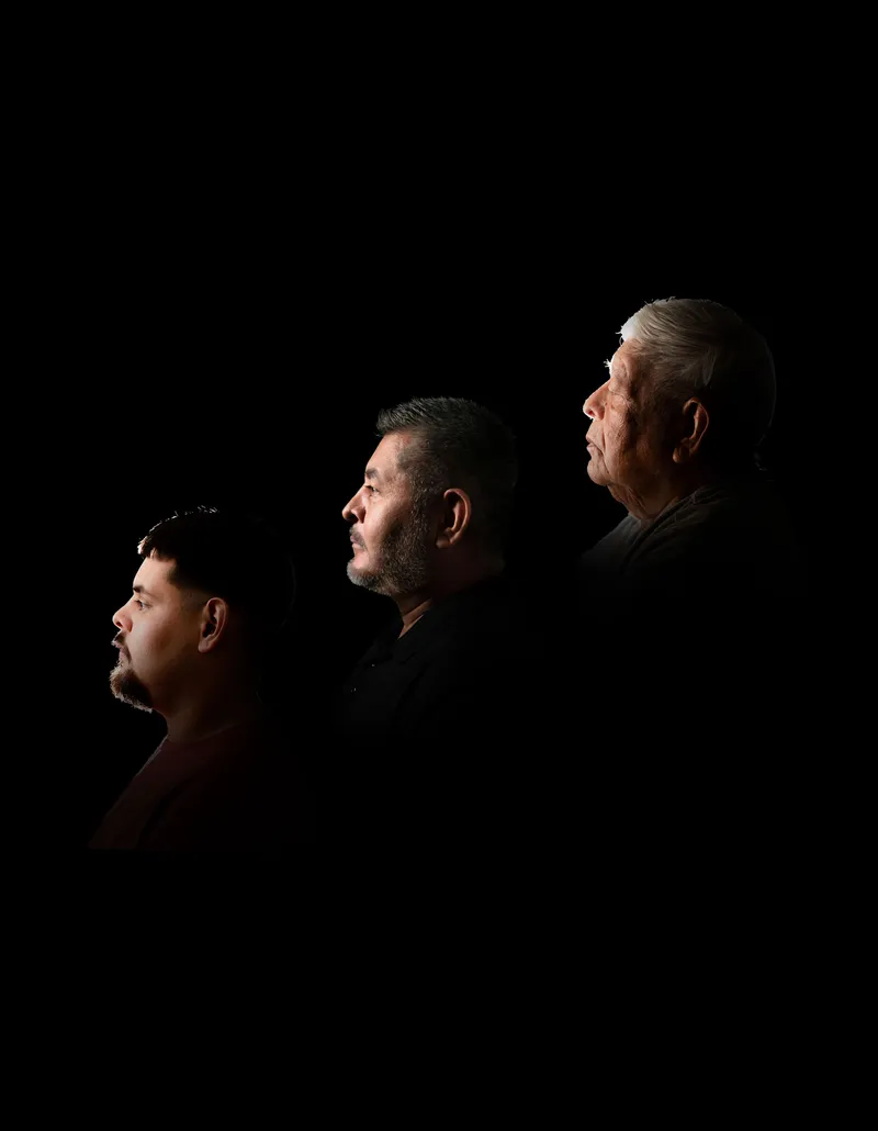 Three generations of men photographed in profile against a black background
