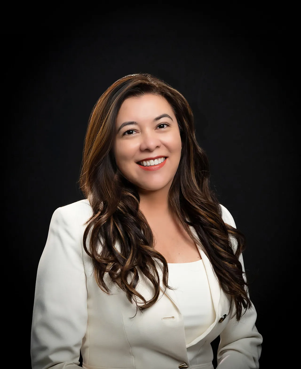 Editorial portrait of a woman in a white blazer against a black backdrop