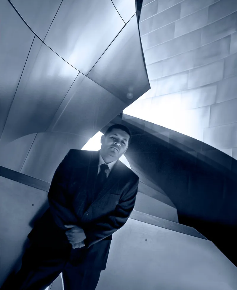 Personal branding portrait of a man in a suit photographed with dramatic architectural lines in blue tone