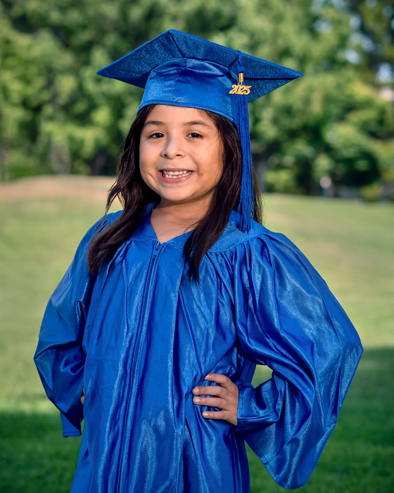 Girl in a blue graduation cap and gown posing for a school portrait in Northridge