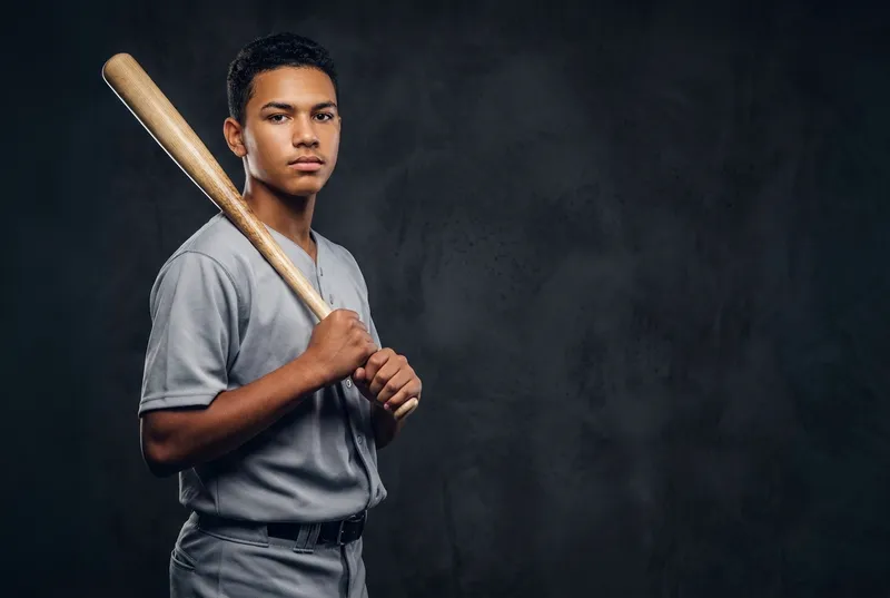 Young baseball player holding a bat over his shoulder in a studio portrait