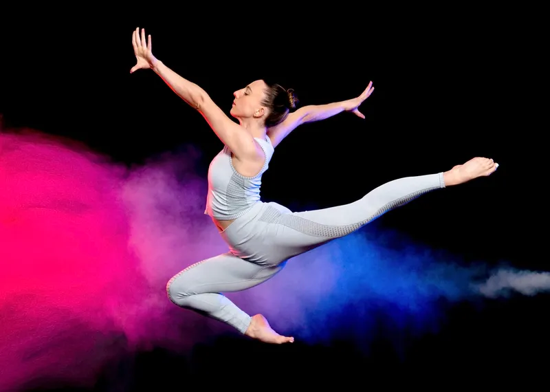 Gymnast leaping through a burst of colored powder for an action portrait