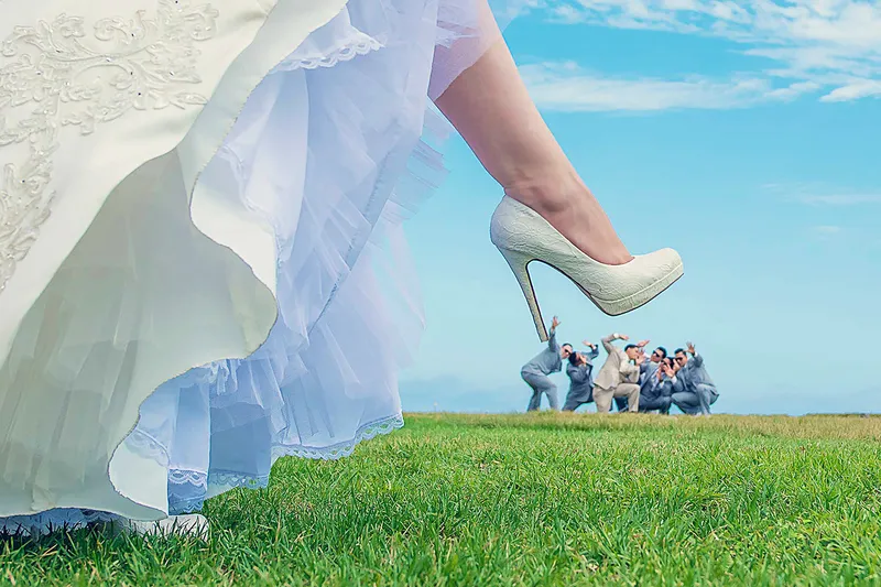 Bride's heel in sharp focus with her groomsmen posing playfully in the background