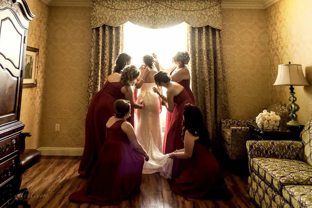 Bridesmaids in red dresses gathered near a window