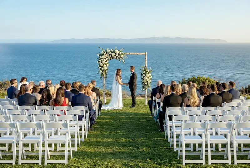Wedding ceremony aisle with guests seated facing an ocean view