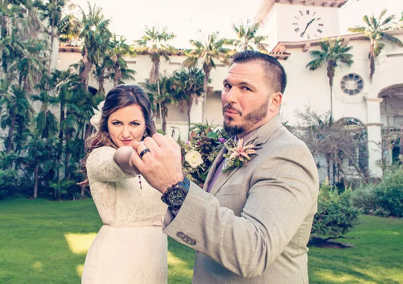 Bride and groom showing off their wedding rings in front of the Santa Barbara courthouse clock tower