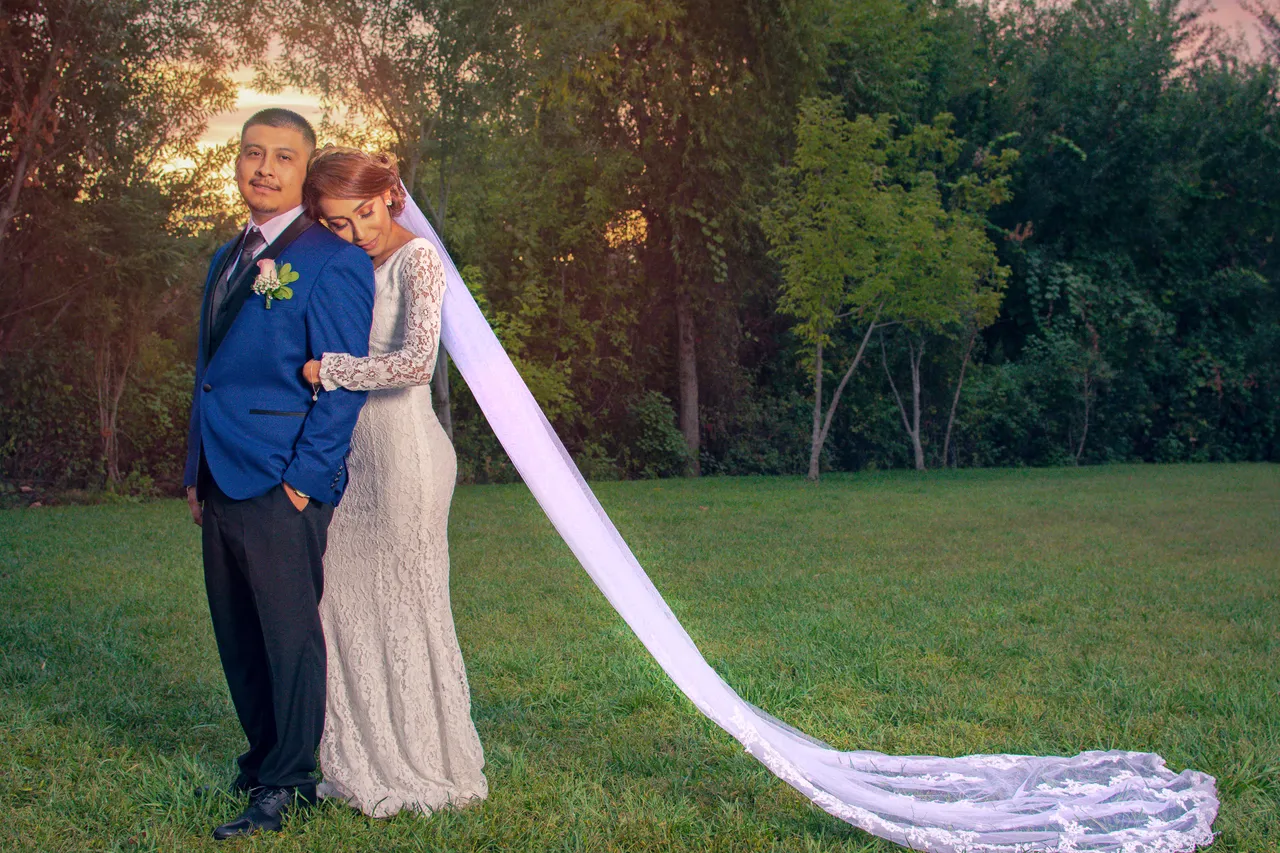 Groom in a blue jacket with the bride's long cathedral veil flowing at golden hour, Northridge wedding photography