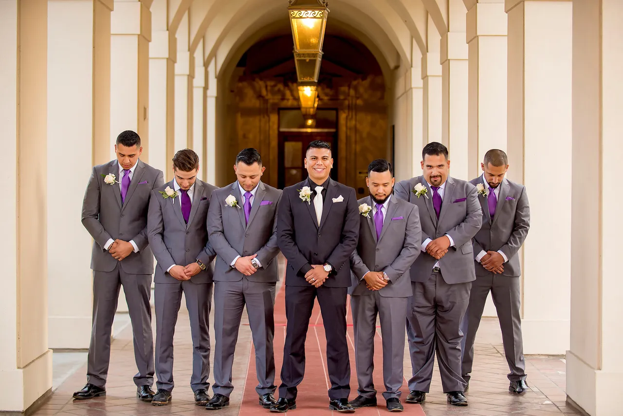 Groomsmen in matching suits with purple ties posing together under a colonnade, Pasadena courthouse