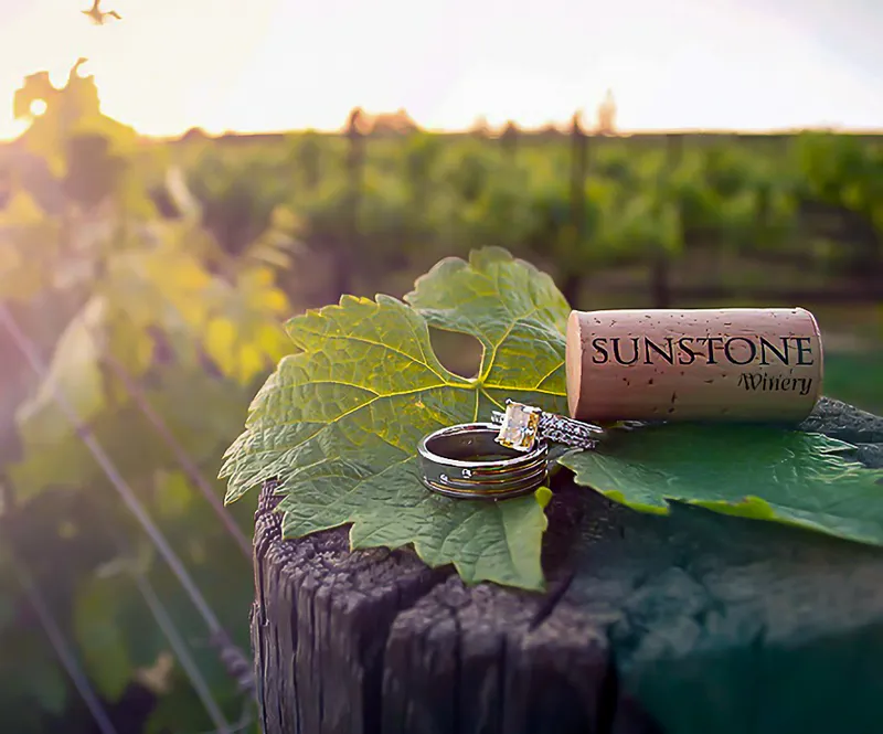 Two rings resting on a grape leaf beside a branded wine cork, Sunstone Winery near Solvang