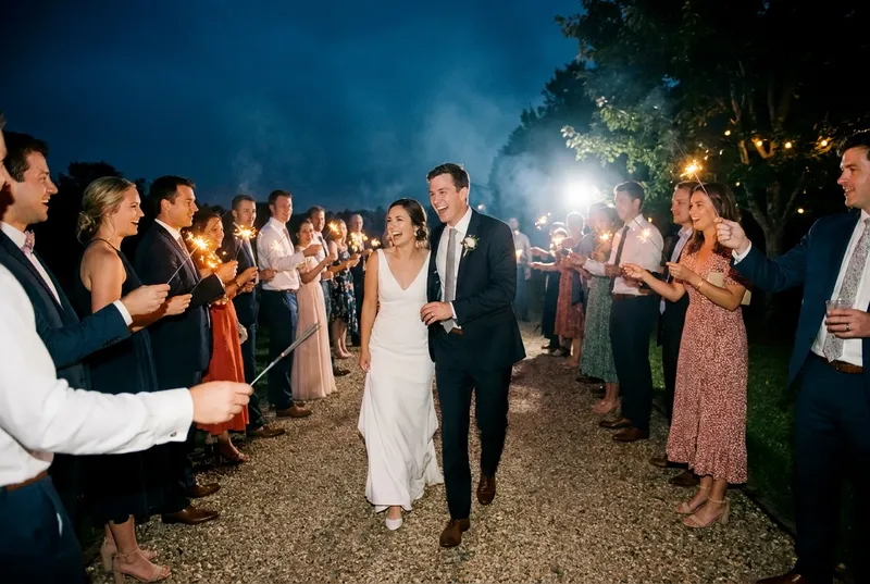Bride and groom walking through a sparkler send-off at night