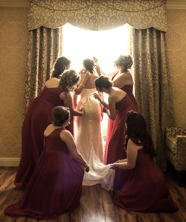 bridal-preperation-with-bridesmaids-fixing-brides-wedding-dress-northridge-photo-studio